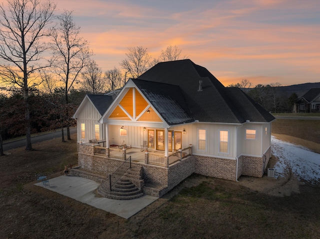 back house at dusk with central AC unit, a patio area, outdoor lounge area, and a lawn