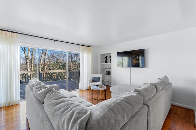 living room featuring baseboards, hardwood / wood-style floors, and built in features