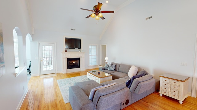 living room featuring ceiling fan, high vaulted ceiling, ornamental molding, and light wood-type flooring