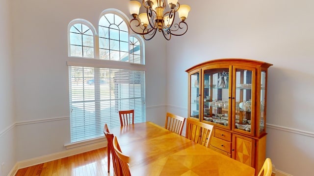 dining area featuring wood-type flooring, a high ceiling, and an inviting chandelier