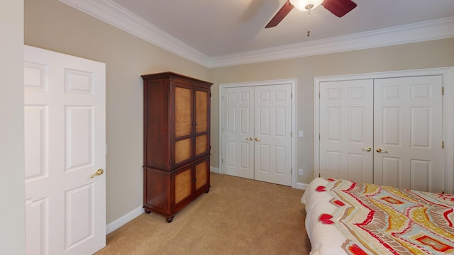 bedroom featuring multiple closets, ceiling fan, crown molding, and light carpet