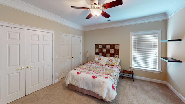 carpeted bedroom featuring ceiling fan, crown molding, multiple windows, and two closets