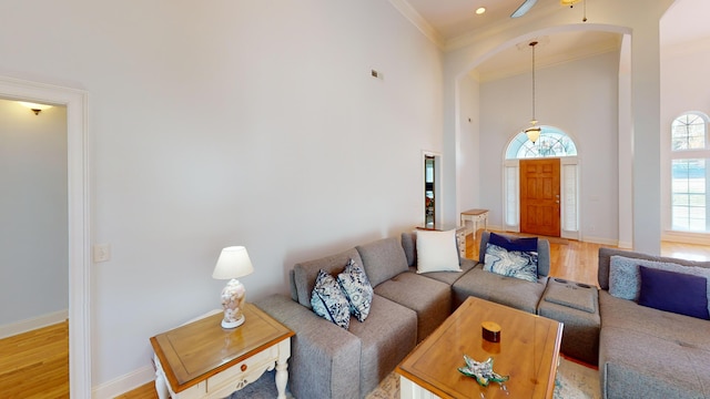 living room featuring a high ceiling, ceiling fan, crown molding, and hardwood / wood-style floors