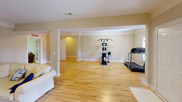 exercise room with light hardwood / wood-style flooring and ornamental molding