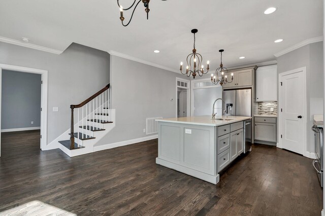 kitchen featuring gray cabinetry, backsplash, a kitchen island with sink, dark hardwood / wood-style flooring, and hanging light fixtures