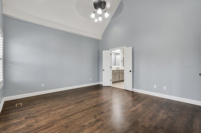 interior space featuring high vaulted ceiling, hardwood / wood-style flooring, ensuite bathroom, and ceiling fan