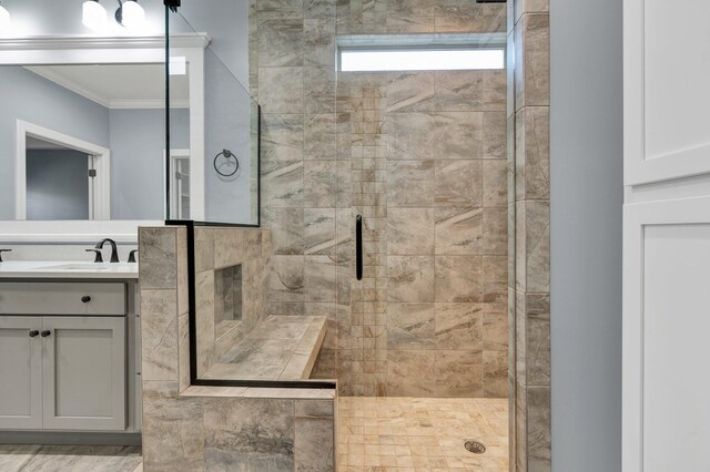 bathroom featuring a shower with shower door, vanity, and ornamental molding