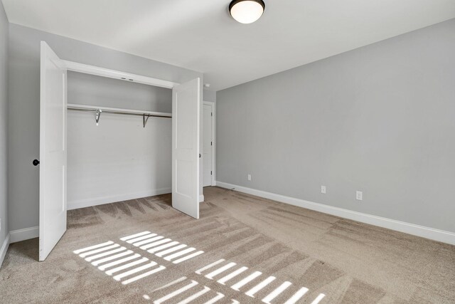 unfurnished bedroom with light carpet and a closet