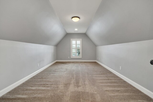 additional living space featuring lofted ceiling and carpet flooring