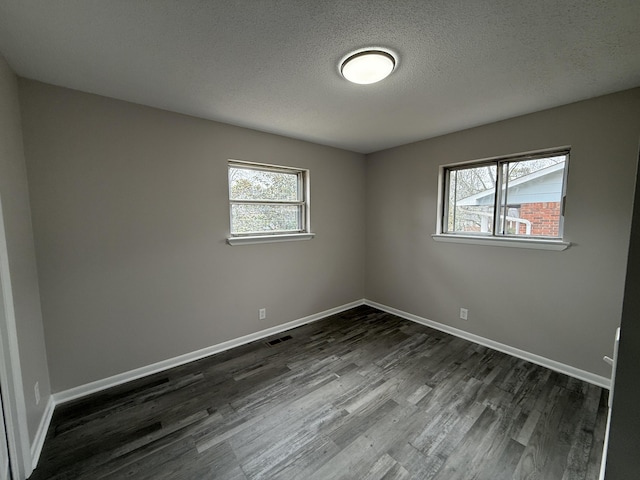 spare room with a textured ceiling and dark wood-type flooring