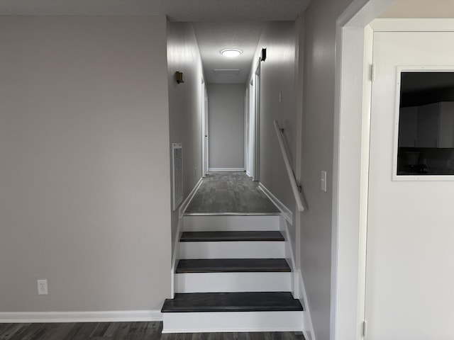 stairs with hardwood / wood-style floors and a textured ceiling