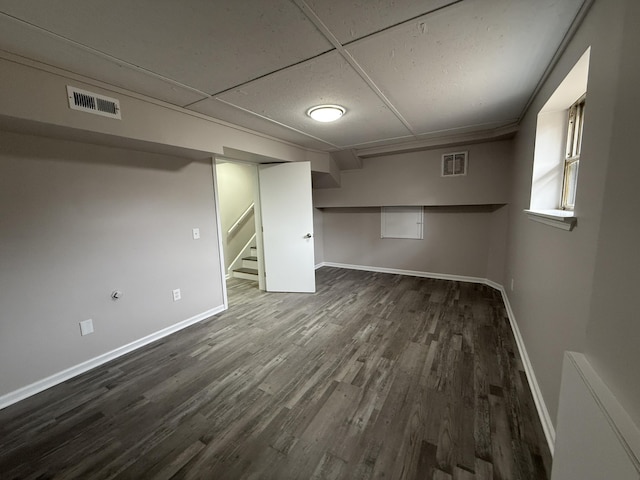 basement featuring a paneled ceiling and dark hardwood / wood-style floors