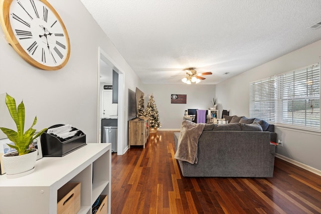 living room with ceiling fan, dark hardwood / wood-style flooring, and a textured ceiling