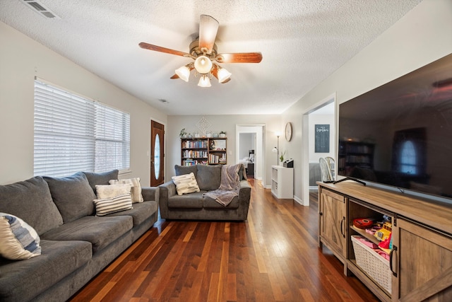 living room with dark hardwood / wood-style floors, ceiling fan, and a textured ceiling