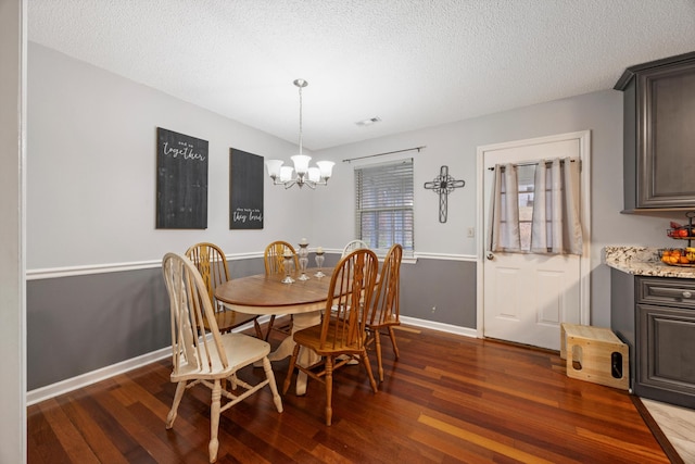 dining space featuring a textured ceiling, dark hardwood / wood-style floors, and an inviting chandelier