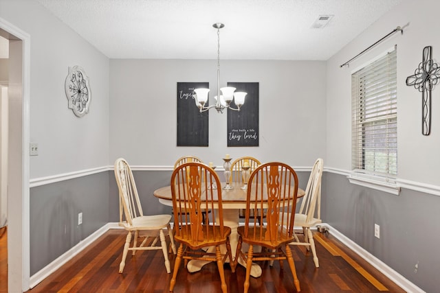 dining room with a notable chandelier, dark hardwood / wood-style flooring, and a textured ceiling