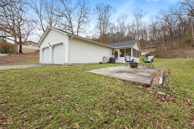 rear view of house featuring central air condition unit, a yard, a patio, a garage, and an outdoor fire pit