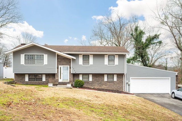 raised ranch featuring a garage and a front lawn