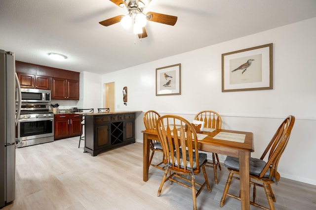 dining room with a textured ceiling, light hardwood / wood-style flooring, and ceiling fan