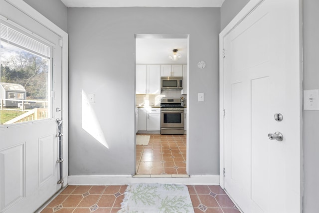 interior space with white cabinets, appliances with stainless steel finishes, tile patterned flooring, and tasteful backsplash