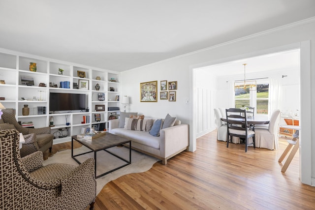 living room with light wood-type flooring, crown molding, and an inviting chandelier