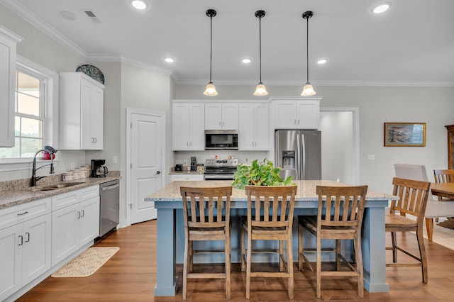 kitchen with hanging light fixtures, sink, stainless steel appliances, and a center island