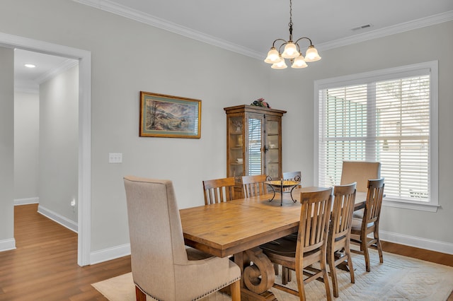 dining space with hardwood / wood-style flooring, crown molding, and a notable chandelier