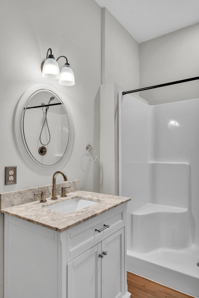 bathroom featuring walk in shower, vanity, and hardwood / wood-style flooring