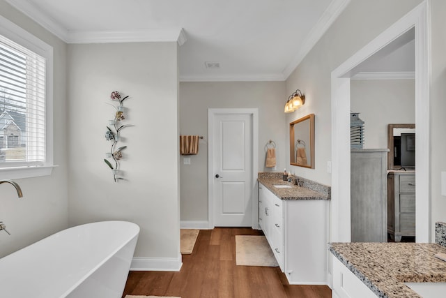 bathroom featuring hardwood / wood-style flooring, vanity, crown molding, and a tub