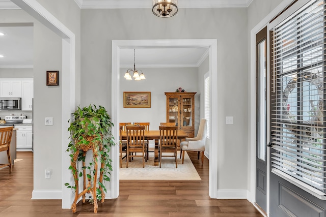 dining space featuring crown molding, hardwood / wood-style floors, and a notable chandelier