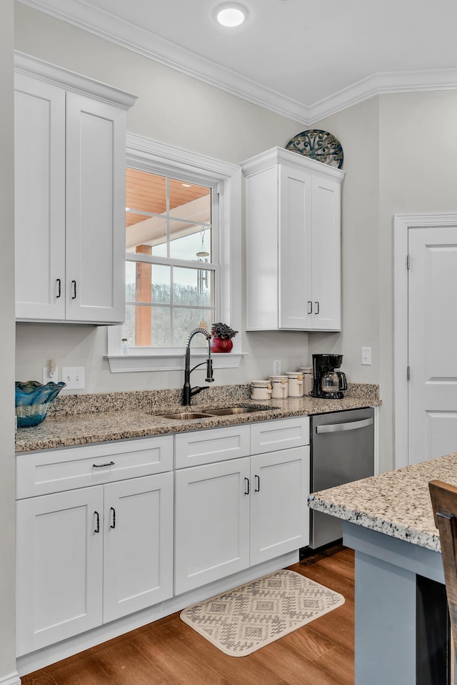 kitchen with sink, wood-type flooring, ornamental molding, white cabinets, and stainless steel dishwasher