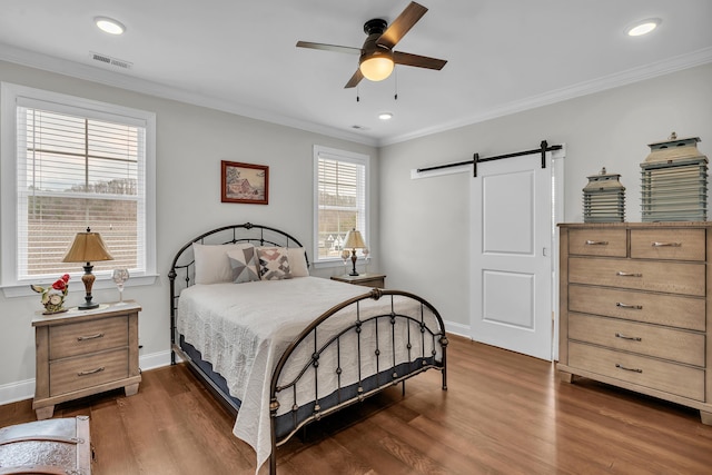 bedroom featuring dark hardwood / wood-style flooring, ornamental molding, a barn door, and ceiling fan