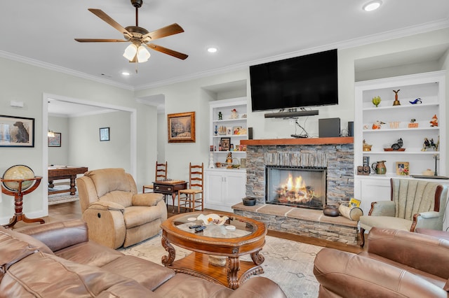 living room featuring crown molding, a stone fireplace, built in features, and ceiling fan