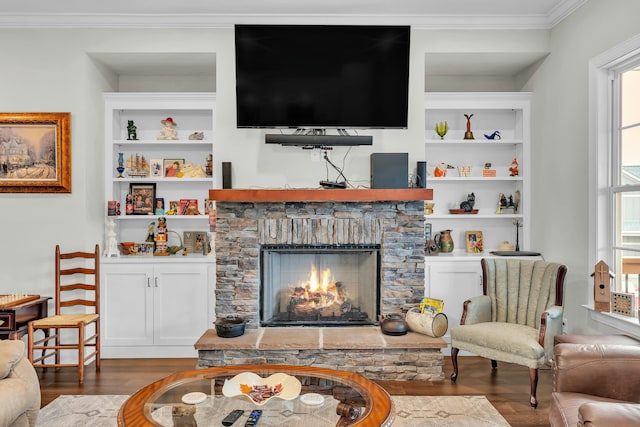 living room with built in shelves, ornamental molding, a fireplace, and dark hardwood / wood-style flooring