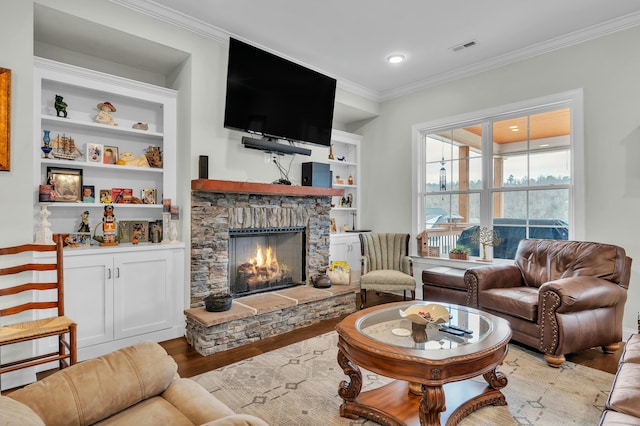 living room featuring ornamental molding, light hardwood / wood-style flooring, a fireplace, and built in shelves