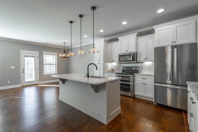 kitchen with pendant lighting, white cabinets, appliances with stainless steel finishes, an island with sink, and sink