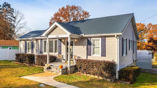 bungalow with covered porch, a front yard, and fence