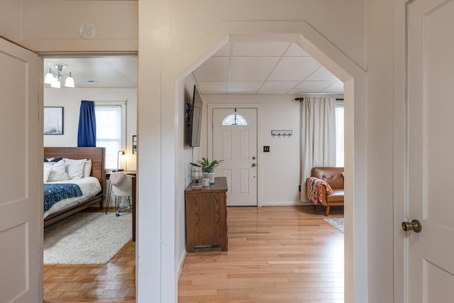 entryway featuring a paneled ceiling, light hardwood / wood-style floors, and an inviting chandelier