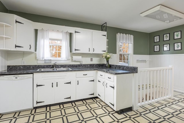 kitchen with white dishwasher, a healthy amount of sunlight, white cabinetry, and sink