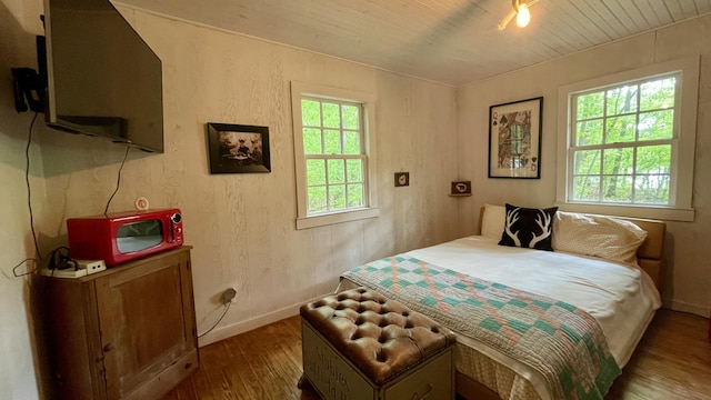 bedroom featuring dark hardwood / wood-style flooring, wooden ceiling, and multiple windows