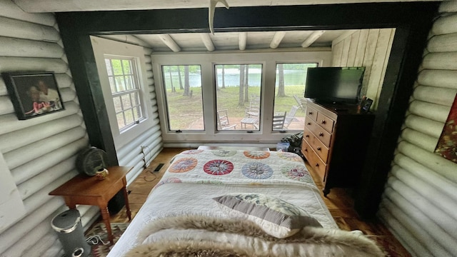 bedroom with hardwood / wood-style floors, beam ceiling, and rustic walls