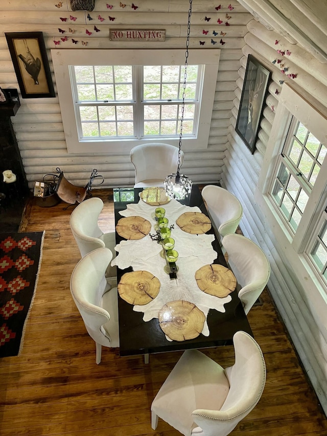 dining room featuring log walls and dark hardwood / wood-style flooring