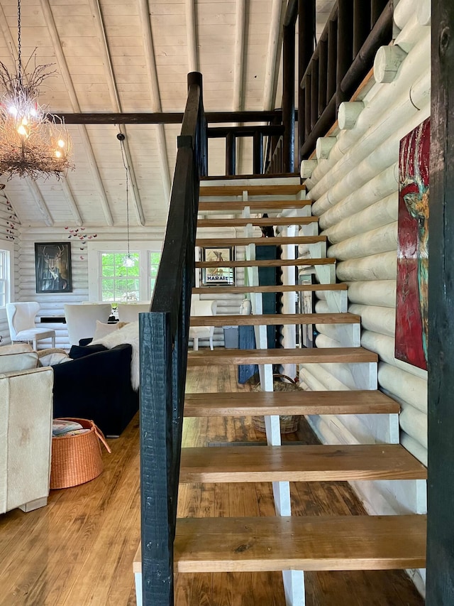 staircase featuring log walls, hardwood / wood-style floors, vaulted ceiling with beams, and wood ceiling