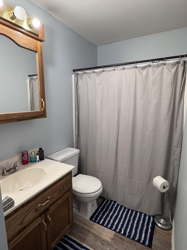 bathroom featuring hardwood / wood-style flooring, vanity, toilet, and a textured ceiling