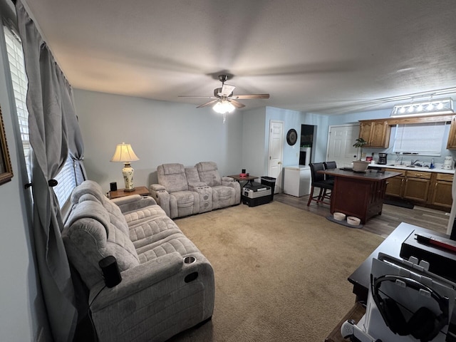 carpeted living room with ceiling fan and sink