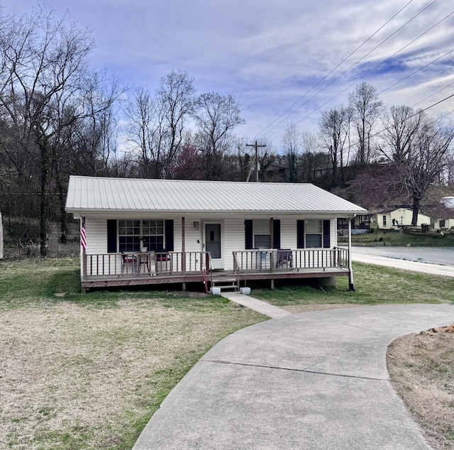 view of front of home with a porch, metal roof, and a front yard