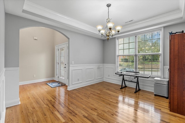 unfurnished dining area featuring a tray ceiling, an inviting chandelier, a wealth of natural light, and crown molding