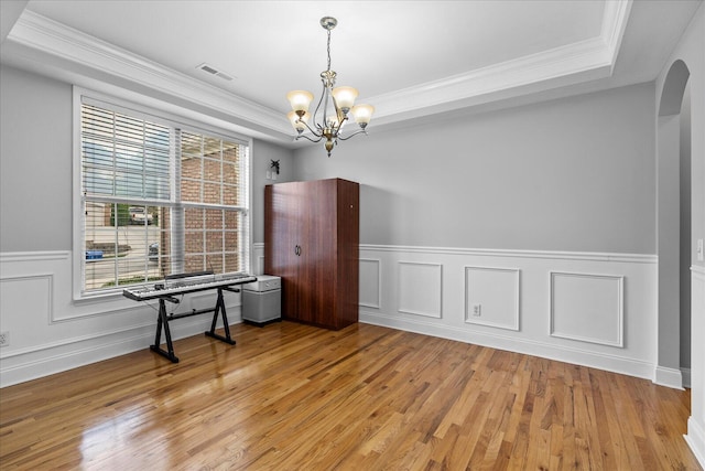 spare room with light wood-type flooring, a tray ceiling, and ornamental molding