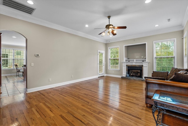 living room with hardwood / wood-style floors, ceiling fan, ornamental molding, and a healthy amount of sunlight