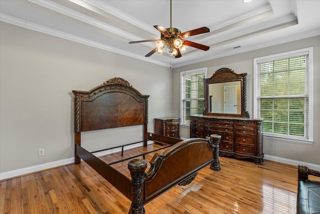 bedroom featuring a raised ceiling, ceiling fan, light wood-type flooring, and ornamental molding